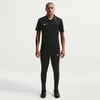 Mann in schwarzem Poloshirt und schwarzer Hose von Nike.