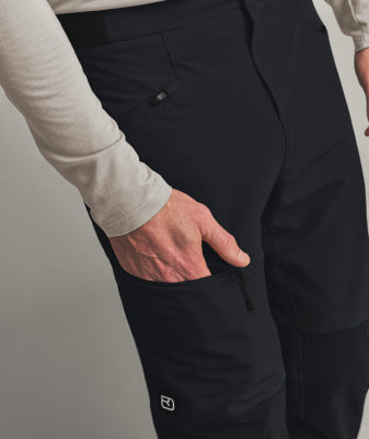 Ein Mann steckt seine Hand in eine schwarze Hosentasche mit Logo. Ein Mann steckt seine Hand in eine schwarze Hosentasche mit Logo.