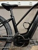 Schwarzes Elektro-Mountainbike mit Pedalen und Kette.