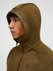 Mann in einem olivgrünen Kapuzenpullover mit Peak Performance Logo auf der Kapuze.