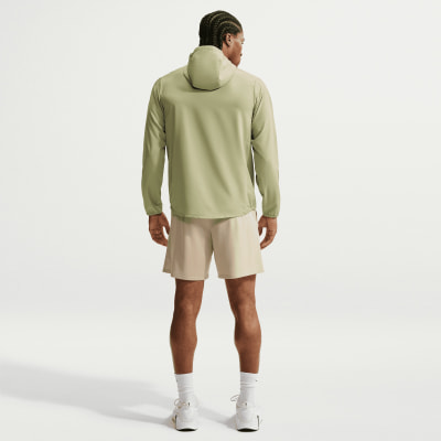 Ein Mann in einer grünen Kapuzenjacke und beige Shorts steht rückwärts. Ein Mann in einer grünen Kapuzenjacke und beige Shorts steht rückwärts.