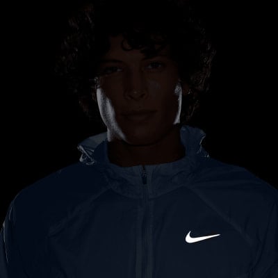 Mann in blauer Jacke mit Nike-Logo, dunkler Hintergrund.