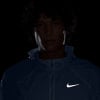 Mann in blauer Jacke mit Nike-Logo, dunkler Hintergrund.