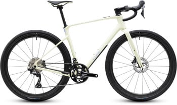 Creme Cube Gravelbike mit schwarzen Rädern und Komponenten.