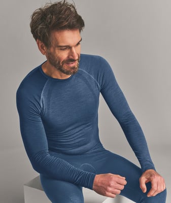 Ein Mann in blauer Thermounterwäsche sitzt und lächelt. Ein Mann in blauer Thermounterwäsche sitzt und lächelt.
