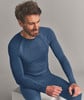 Ein Mann in blauer Thermounterwäsche sitzt und lächelt.
