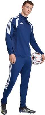 Ein Mann im dunkelblauen Adidas Trainingsanzug hält einen Fußball.
