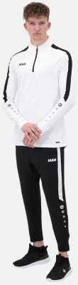 Ein Mann in einem weißen Langarmshirt und einer schwarzen Trainingshose mit Streifen. Ein Mann in einem weißen Langarmshirt und einer schwarzen Trainingshose mit Streifen.