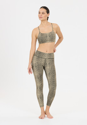 Eine Frau in leopardartiger Sportkleidung steht vor weißem Hintergrund. Eine Frau in leopardartiger Sportkleidung steht vor weißem Hintergrund.