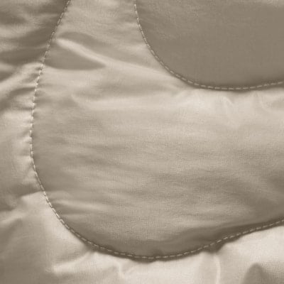 Detail eines gesteppten beigen Stoffes mit leichtem Glanz. Detail eines gesteppten beigen Stoffes mit leichtem Glanz.