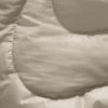 Detail eines gesteppten beigen Stoffes mit leichtem Glanz.