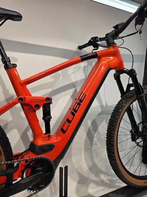 Orange E-Bike der Marke CUBE mit Federung und schwarzen Details. Orange E-Bike der Marke CUBE mit Federung und schwarzen Details.