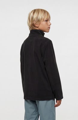 Ein Junge in einem dunklen Fleece-Pullover mit hohem Kragen und blauer Hose. Ein Junge in einem dunklen Fleece-Pullover mit hohem Kragen und blauer Hose.