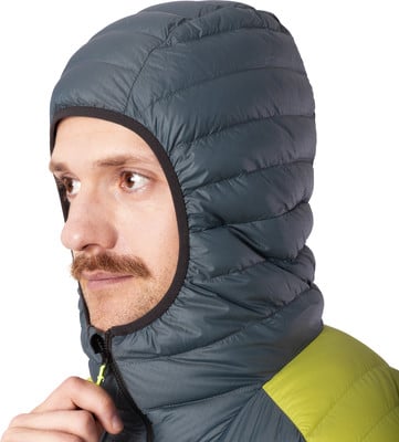 Ein Mann in einer grauen Daunenjacke mit Kapuze und gelbem Detail. Ein Mann in einer grauen Daunenjacke mit Kapuze und gelbem Detail.