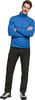 Ein Mann in einer blauen Jacke und schwarzen Hosen mit verschränkten Armen.