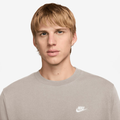 Ein junger Mann mit blonden Haaren und einem Nike-T-Shirt vor neutralem Hintergrund. Ein junger Mann mit blonden Haaren und einem Nike-T-Shirt vor neutralem Hintergrund.