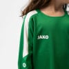 Mädchen in einem grünen T-Shirt mit weißem Streifen am Ärmel und JAKO-Logo.