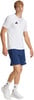 Ein junger Mann in einem weißen T-Shirt und dunkelblauen Shorts mit Turnschuhen.
