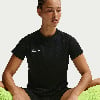 Eine Frau in einem schwarzen Nike-T-Shirt mit Logo sitzt auf dem Boden.