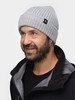 Ein Mann in einer grauen Strickmütze und schwarzer Jacke lächelt.