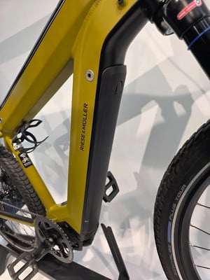 Gelbes Riese & Müller E-Bike mit schwarzer Batterieabdeckung und Schriftzug. Gelbes Riese & Müller E-Bike mit schwarzer Batterieabdeckung und Schriftzug.
