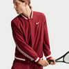 Ein Mann in einer roten Nike-Jacke mit einem Tennisschläger in der Hand.