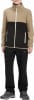 Ein Junge in einer schwarzen Hose und einer beige-schwarzen Fleecejacke mit weißem Reißverschluss.