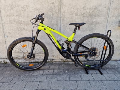 Grünes E-Mountainbike auf einem Ständer vor einer Betonwand. Grünes E-Mountainbike auf einem Ständer vor einer Betonwand.