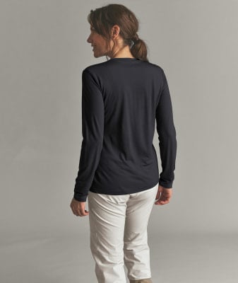 Eine Frau in einem schwarzen Langarmshirt und beiger Hose steht mit dem Rücken zur Kamera. Eine Frau in einem schwarzen Langarmshirt und beiger Hose steht mit dem Rücken zur Kamera.