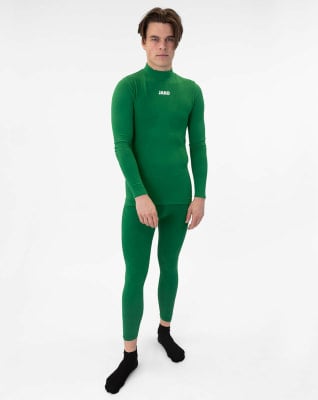 Ein Mann in einem grünen Langarmshirt und Leggings vor weißem Hintergrund.