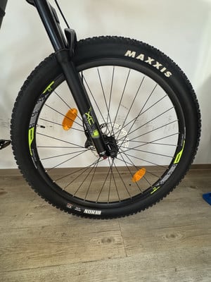 Vorderreifen eines Mountainbikes mit schwarzem Maxxis-Reifen und Federgabel. Vorderreifen eines Mountainbikes mit schwarzem Maxxis-Reifen und Federgabel.