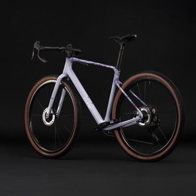 Lila Gravelbike mit buntem Muster auf dem Rahmen und braunen Laufrädern.