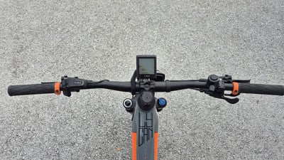 Lenker eines Mountain-E-Bikes mit Display und Griffen auf Asphalt. Lenker eines Mountain-E-Bikes mit Display und Griffen auf Asphalt.