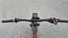 Lenker eines Mountain-E-Bikes mit Display und Griffen auf Asphalt.