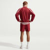 Mann in roter Jacke und Shorts mit weißen Streifen auf dem Rücken.