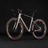 Ein beiger Gravelbike mit braunen Reifen und schwarzen Zipp-Felgen.