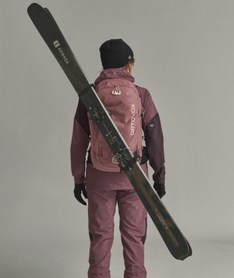 Frau mit Skiern auf dem Rücken in Winterkleidung