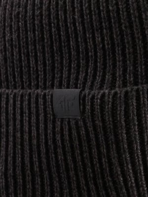 Detail einer dunklen Strickmütze mit kleinem schwarzem Logo-Etikett. Detail einer dunklen Strickmütze mit kleinem schwarzem Logo-Etikett.
