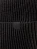 Detail einer dunklen Strickmütze mit kleinem schwarzem Logo-Etikett.
