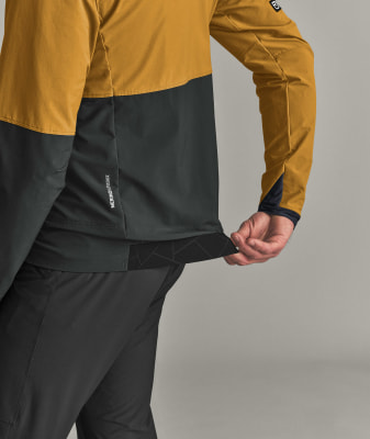 Ein Mann zieht am Bund eine schwarze Stoffpartie mit geometrischem Muster hoch. Ein Mann zieht am Bund eine schwarze Stoffpartie mit geometrischem Muster hoch.