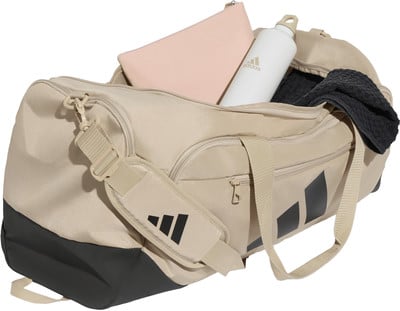 Beige Adidas Sporttasche mit schwarzen Streifen und Zubehör. Beige Adidas Sporttasche mit schwarzen Streifen und Zubehör.