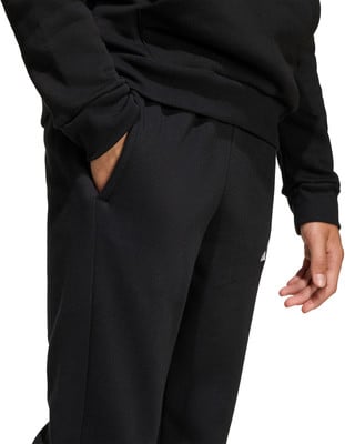 Detail einer schwarzen Sporthose mit einer Tasche und einer Hand darin. Detail einer schwarzen Sporthose mit einer Tasche und einer Hand darin.