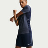 Ein Mann in einem dunkelblauen Shirt und Shorts dehnt seinen Arm.