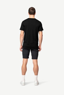 Ein Mann in einem schwarzen T-Shirt und dunklen Shorts steht mit dem Rücken zum Betrachter.