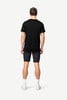Ein Mann in einem schwarzen T-Shirt und dunklen Shorts steht mit dem Rücken zum Betrachter.