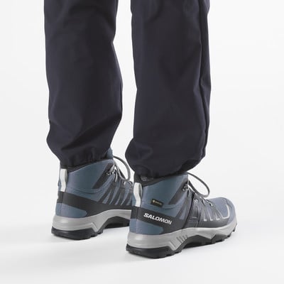 Blick auf Beine in dunklen Hosen und modernen Salomon Wanderschuhen. Blick auf Beine in dunklen Hosen und modernen Salomon Wanderschuhen.