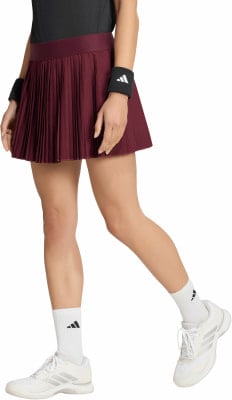 Tennisspielerin im burgunderroten Faltenrock mit weißen Socken und Schuhen. Tennisspielerin im burgunderroten Faltenrock mit weißen Socken und Schuhen.