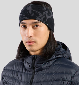 Ein Mann mit langen dunklen Haaren trägt eine schwarze Mütze und eine dunkle Daunenjacke.