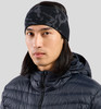 Ein Mann mit langen dunklen Haaren trägt eine schwarze Mütze und eine dunkle Daunenjacke.