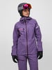 Frau in lila Skijacke und Hose mit Helm und Brille.